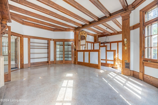 empty room featuring ornate columns, beamed ceiling, and a healthy amount of sunlight