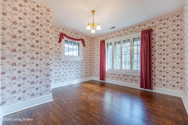 unfurnished room with a notable chandelier and dark wood-type flooring