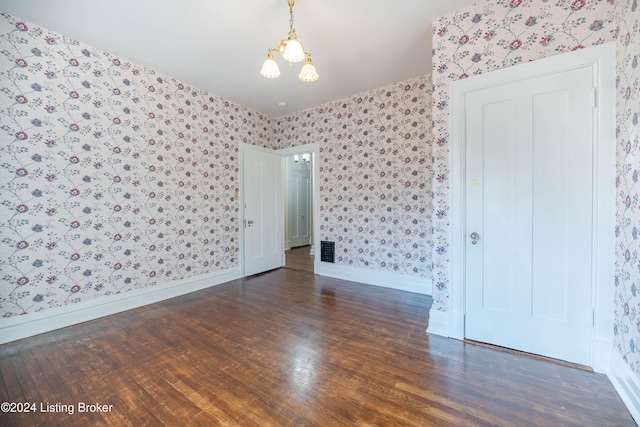 unfurnished room featuring a chandelier and dark hardwood / wood-style flooring