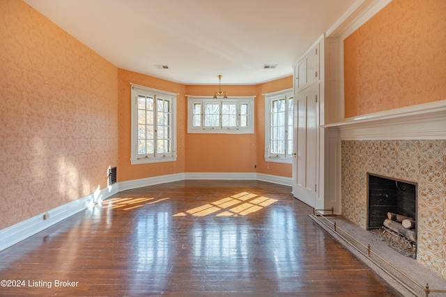 unfurnished living room featuring dark hardwood / wood-style floors, a fireplace, and an inviting chandelier