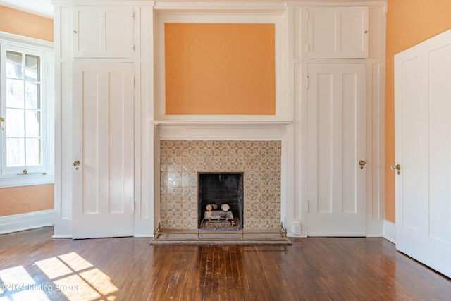 unfurnished living room with dark wood-type flooring and a tile fireplace