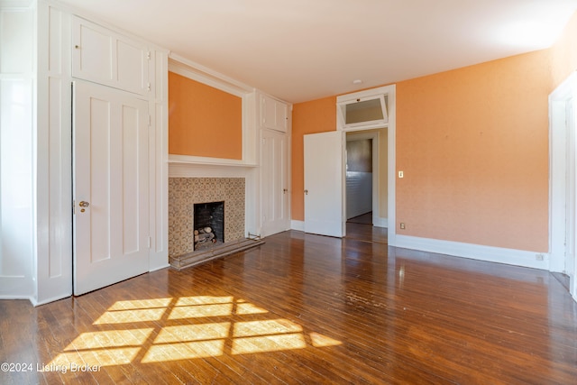 unfurnished living room with a tile fireplace and dark hardwood / wood-style floors