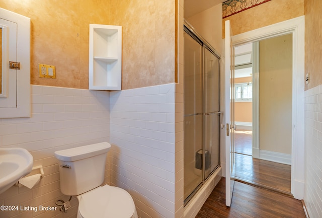 bathroom with hardwood / wood-style flooring, toilet, walk in shower, and tile walls