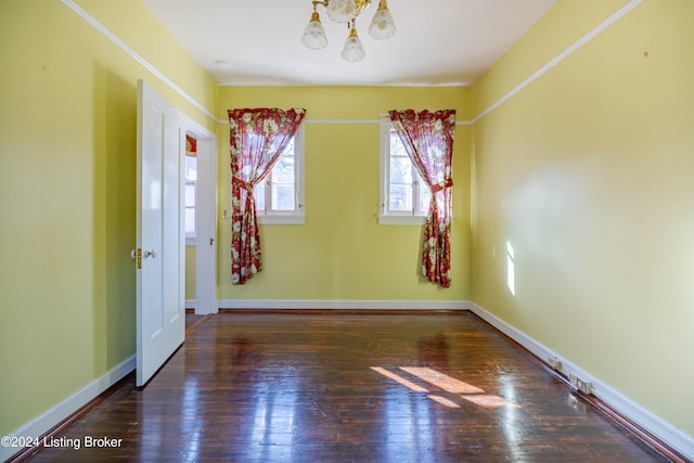 unfurnished room featuring dark hardwood / wood-style floors and a chandelier