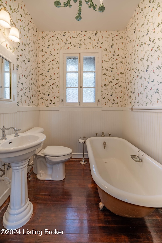 bathroom with hardwood / wood-style floors, sink, toilet, and a tub to relax in