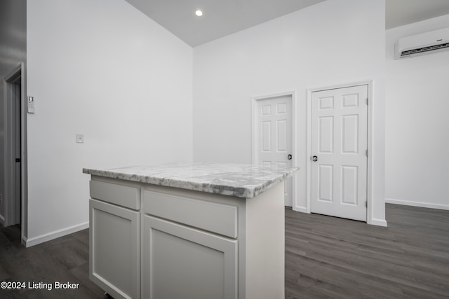 kitchen featuring a towering ceiling, dark hardwood / wood-style floors, light stone counters, and a wall mounted air conditioner