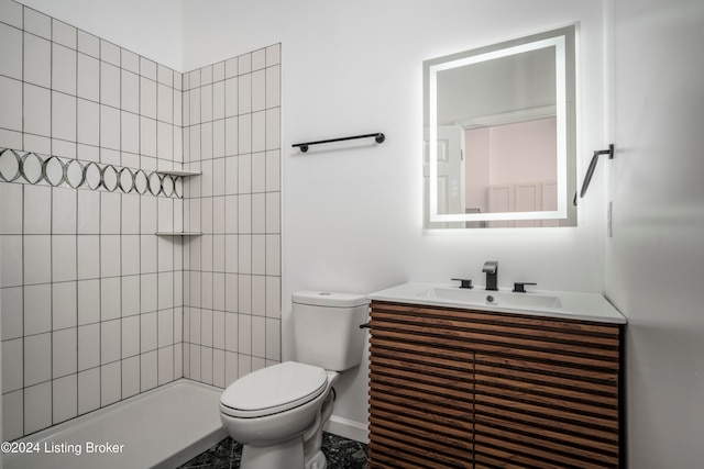 bathroom with vanity, toilet, and tiled shower