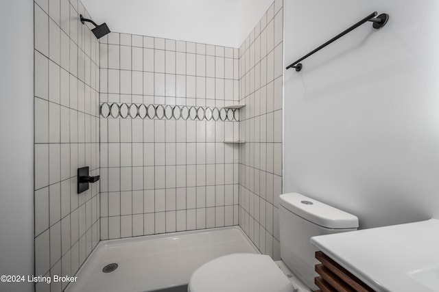 bathroom featuring toilet, vanity, and a tile shower