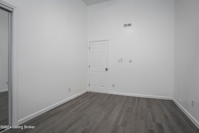 unfurnished room featuring a towering ceiling and dark hardwood / wood-style flooring