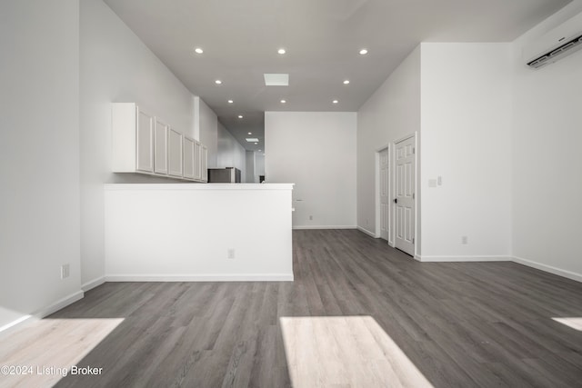 unfurnished living room featuring wood-type flooring and a wall mounted air conditioner