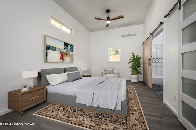 bedroom with dark hardwood / wood-style flooring, a barn door, a wall mounted air conditioner, and ceiling fan