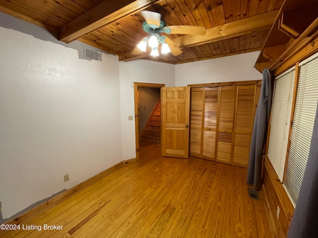 unfurnished bedroom with light hardwood / wood-style flooring, beam ceiling, wood ceiling, and a closet