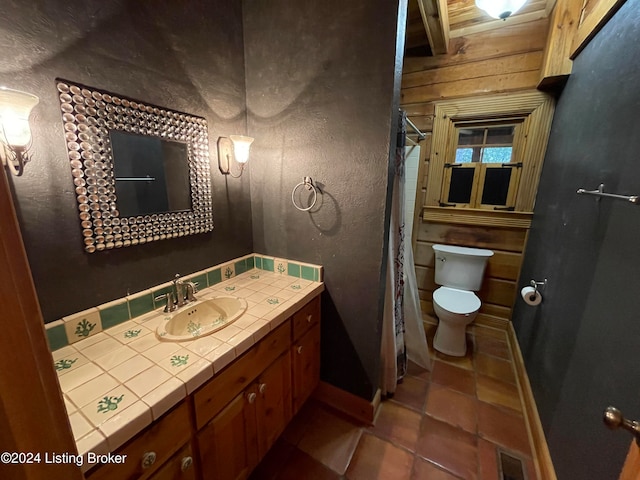 bathroom featuring wood walls, tile patterned floors, toilet, and vanity