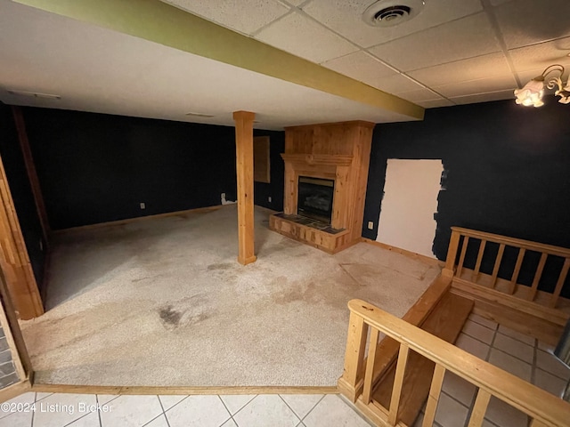 basement with tile patterned floors, a large fireplace, and a drop ceiling