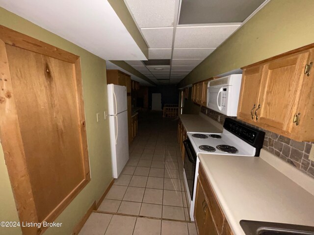 kitchen featuring white appliances, light tile patterned floors, backsplash, and a drop ceiling