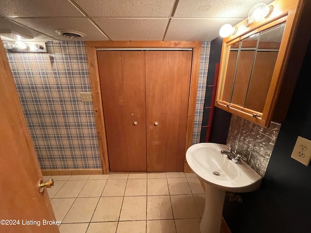 bathroom with tile patterned floors, sink, and a drop ceiling