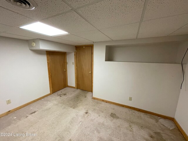 basement with light colored carpet and a paneled ceiling