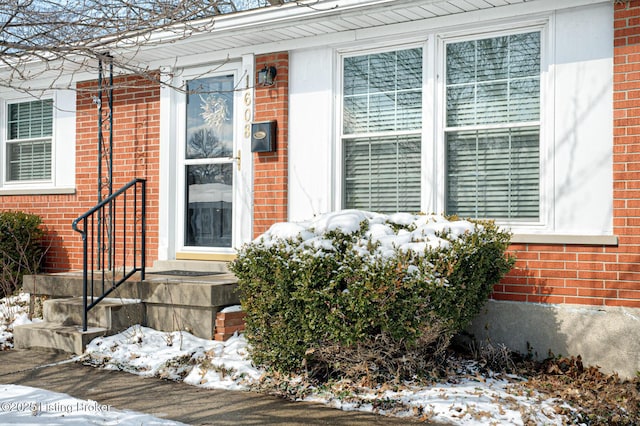 snow covered property entrance with brick siding