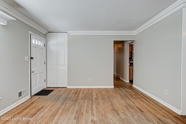 unfurnished room with light wood finished floors, visible vents, and crown molding