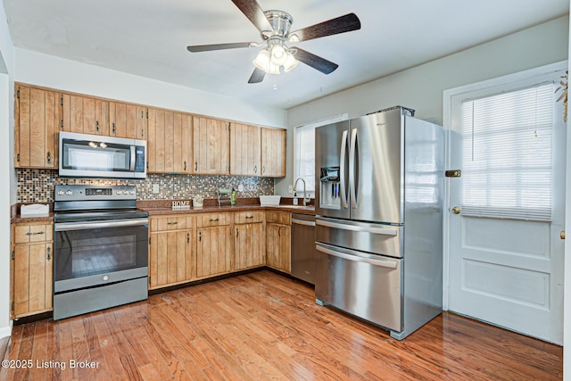 kitchen featuring light wood-type flooring, plenty of natural light, tasteful backsplash, and stainless steel appliances