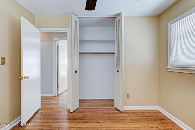 unfurnished bedroom featuring a closet, a ceiling fan, a textured ceiling, wood finished floors, and baseboards