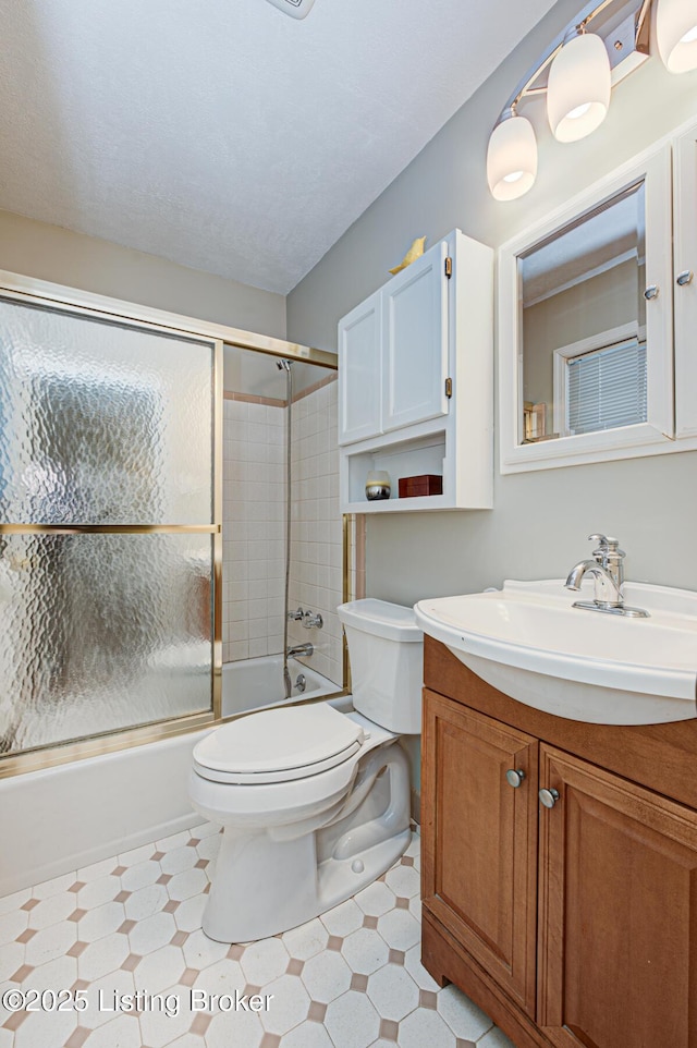 bathroom with combined bath / shower with glass door, vanity, toilet, and tile patterned floors