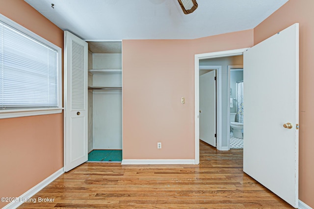 unfurnished bedroom with light wood-type flooring, baseboards, and a closet