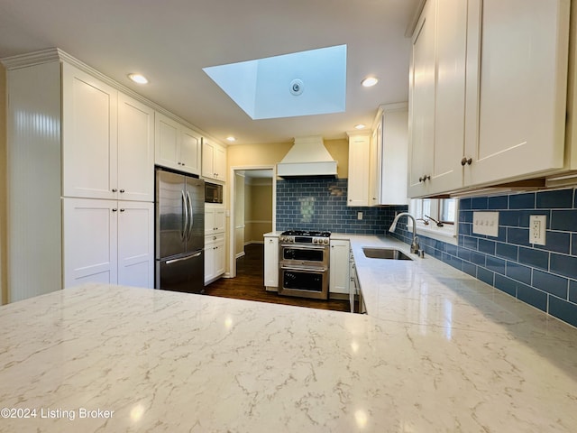 kitchen with white cabinetry, light stone countertops, sink, stainless steel appliances, and custom exhaust hood