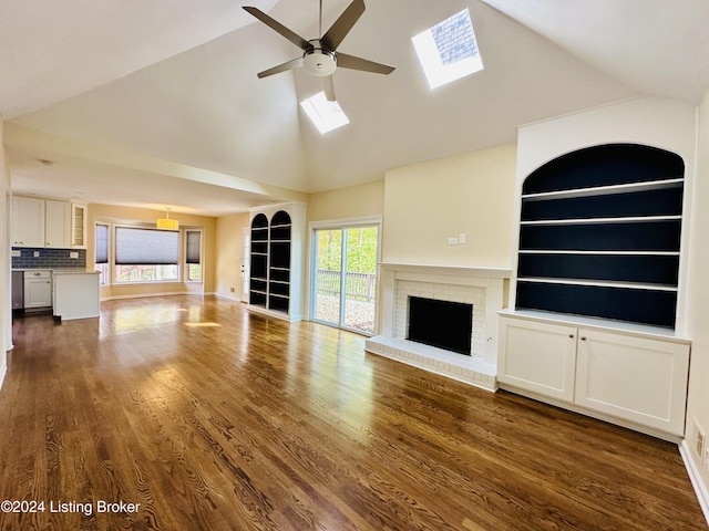 unfurnished living room featuring a brick fireplace, a skylight, ceiling fan, dark hardwood / wood-style floors, and built in features