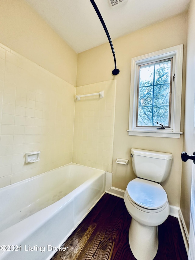 bathroom with hardwood / wood-style flooring, toilet, and tiled shower / bath