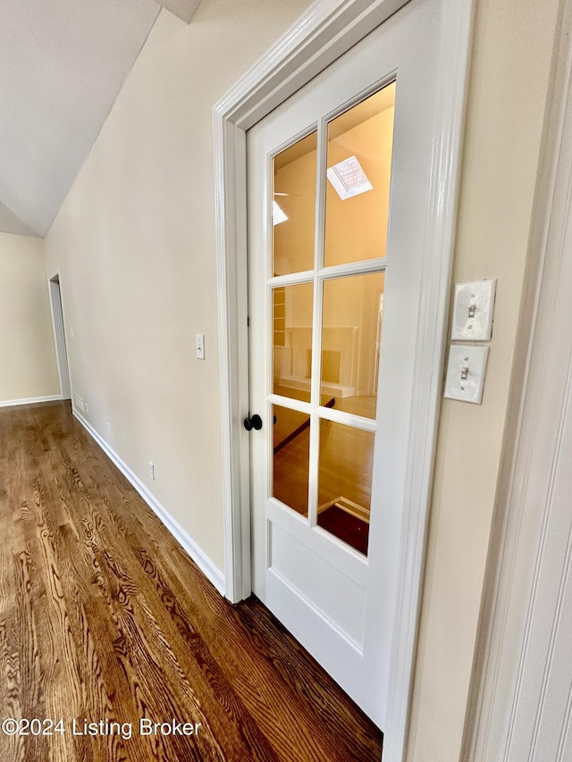 corridor featuring wood-type flooring and vaulted ceiling