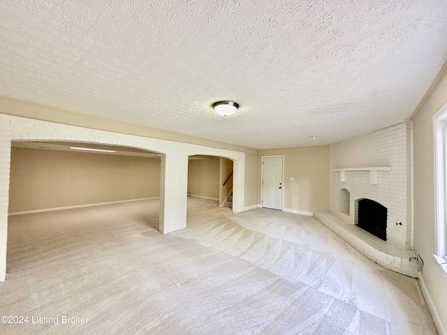 unfurnished living room with carpet floors, a textured ceiling, and a brick fireplace