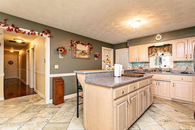 kitchen featuring a breakfast bar area, sink, backsplash, and a kitchen island