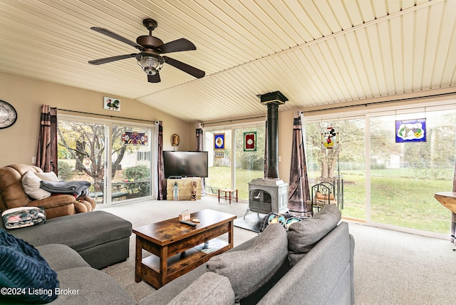 living room featuring lofted ceiling, a wood stove, light carpet, and plenty of natural light