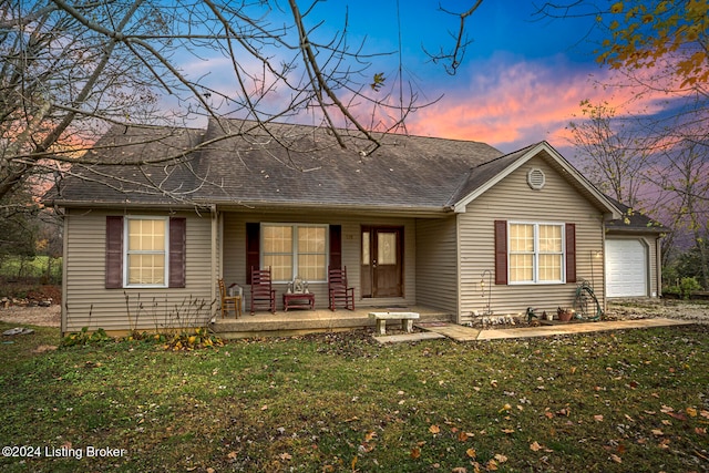 single story home featuring a lawn, a garage, and a porch