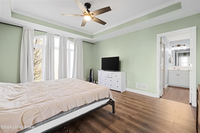 bedroom featuring ceiling fan, dark hardwood / wood-style floors, multiple windows, and a tray ceiling