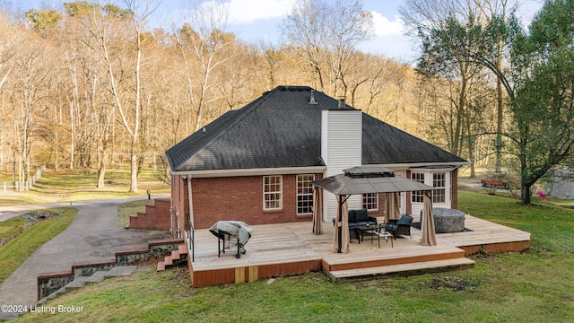 rear view of property with a deck, a yard, and a gazebo