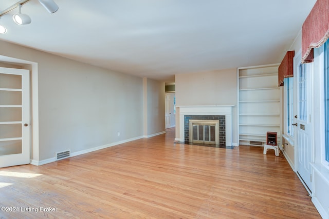 unfurnished living room with a fireplace, light hardwood / wood-style flooring, and rail lighting