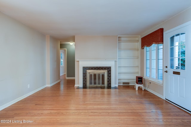 unfurnished living room featuring a brick fireplace and light hardwood / wood-style flooring