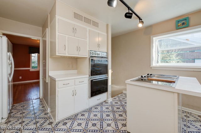 kitchen with white cabinets, rail lighting, white appliances, and a breakfast bar