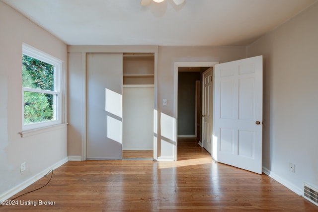 unfurnished bedroom with hardwood / wood-style floors, ceiling fan, and a closet