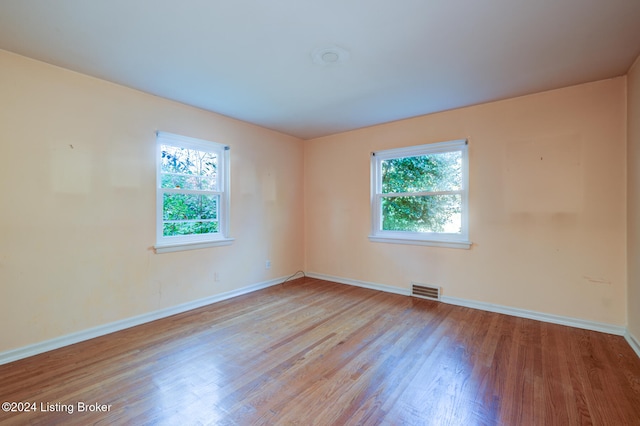 spare room with plenty of natural light and light hardwood / wood-style flooring