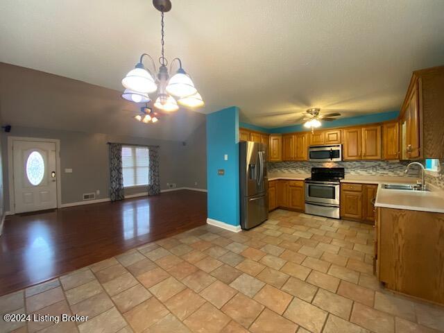 kitchen with light hardwood / wood-style floors, hanging light fixtures, sink, backsplash, and appliances with stainless steel finishes