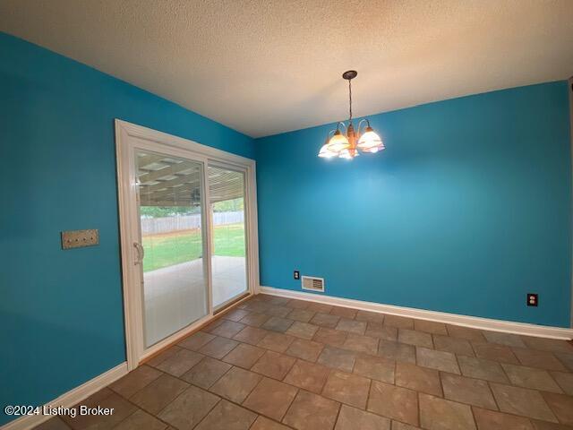 unfurnished dining area featuring a textured ceiling, tile patterned floors, and a notable chandelier