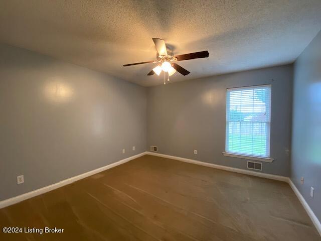 spare room featuring ceiling fan, a textured ceiling, and carpet