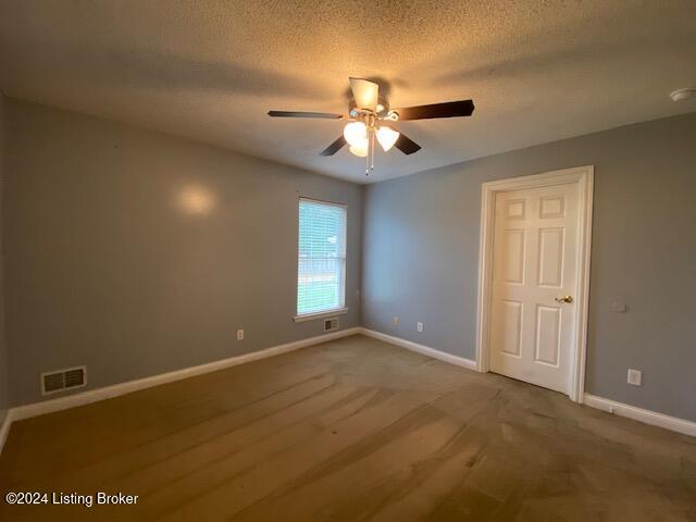 empty room featuring ceiling fan, a textured ceiling, and carpet flooring