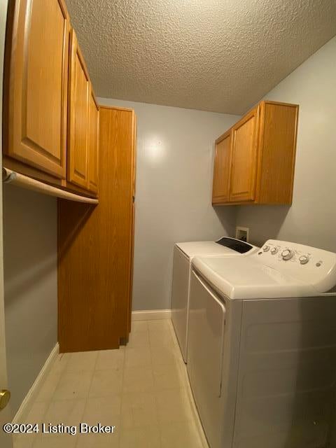 clothes washing area featuring cabinets, a textured ceiling, and washer and dryer