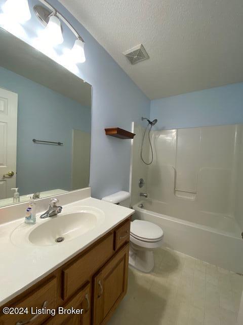 full bathroom featuring toilet, washtub / shower combination, vanity, and a textured ceiling