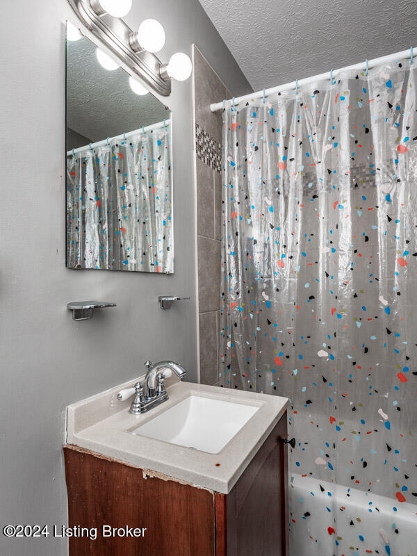 bathroom with walk in shower, vanity, and a textured ceiling