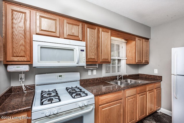 kitchen featuring white appliances, a textured ceiling, and sink